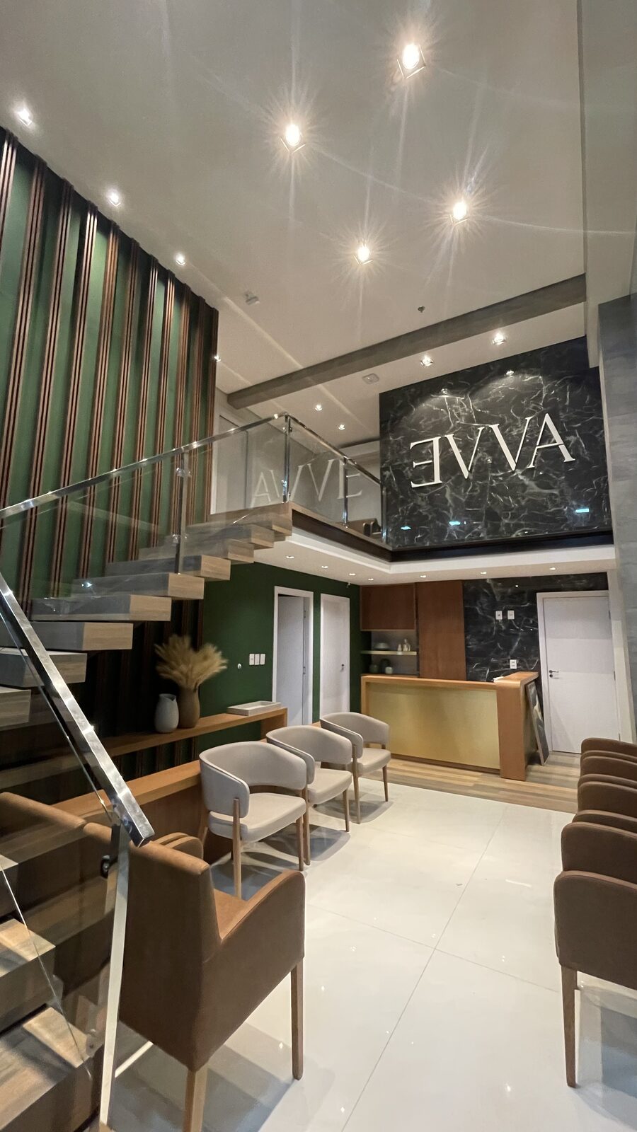 Recepção da Clínica Evva com pé-direito duplo e logotipo em mármore
